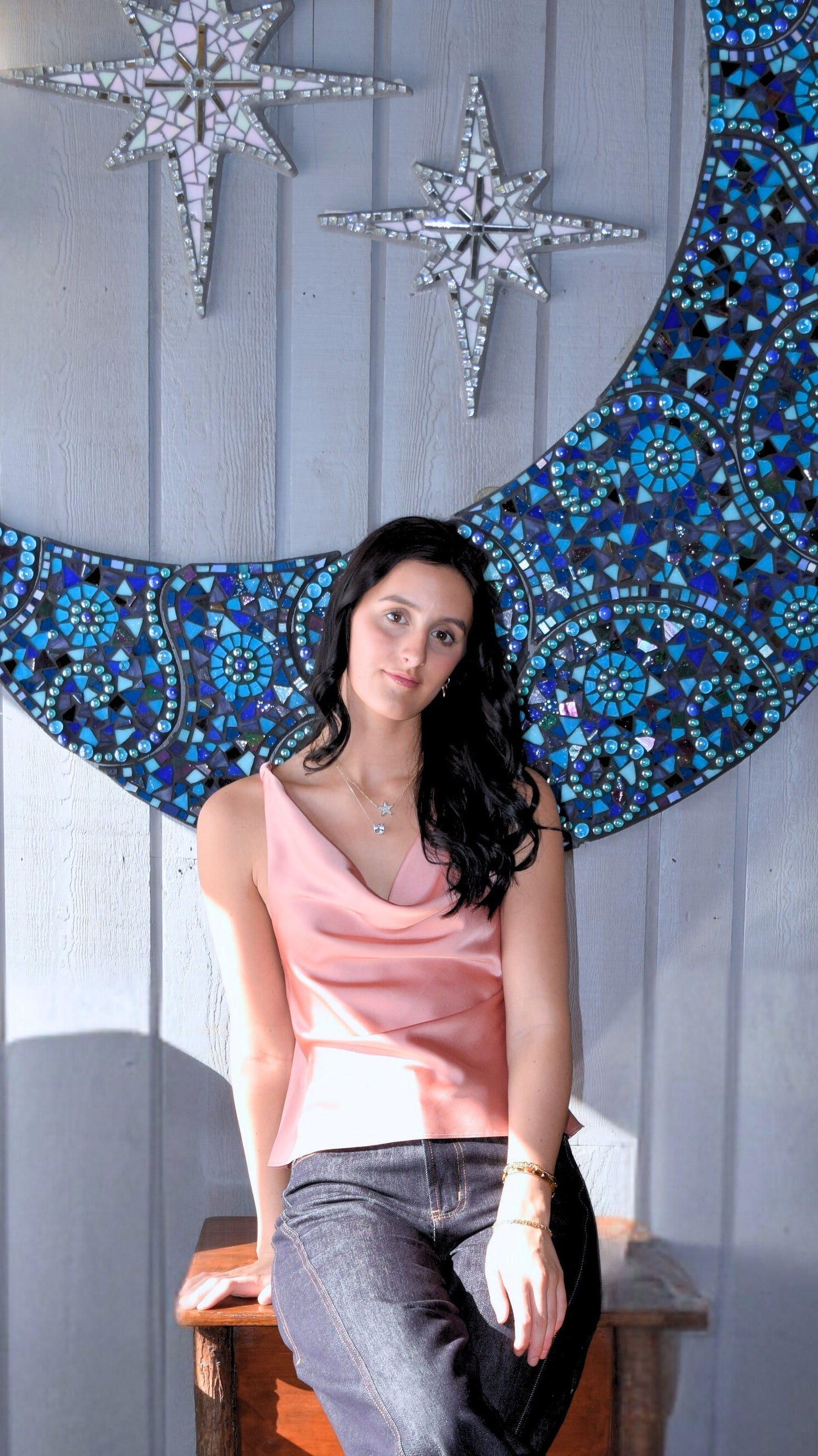 Woman wearing a satin drape neck top with dark jeans