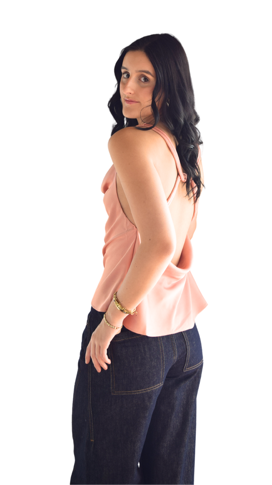 Woman wearing a satin open back top with dark wash jean 